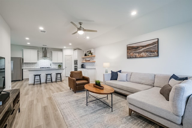 living room with ceiling fan and light wood-type flooring