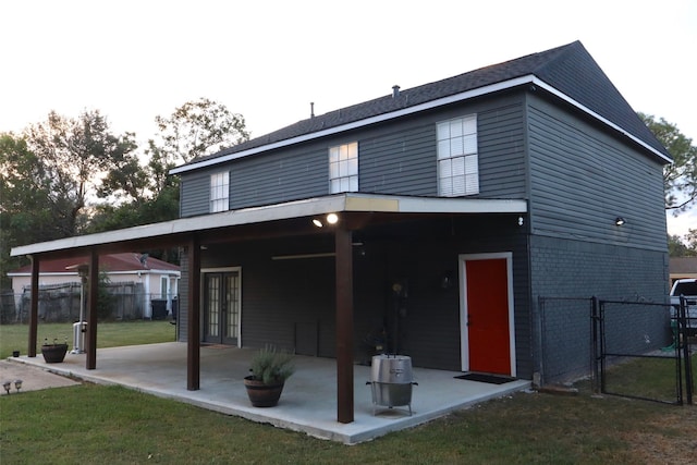 back of property featuring brick siding, a yard, a gate, a patio area, and fence