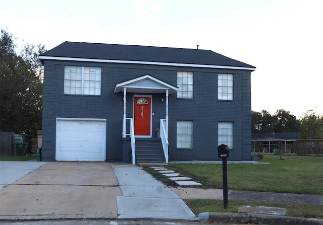 raised ranch with a garage, driveway, brick siding, and a front yard