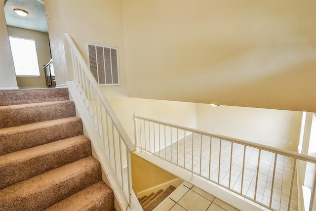 stairway featuring tile patterned flooring and visible vents