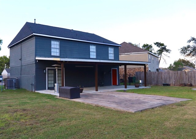 back of property featuring a patio, central AC unit, brick siding, fence, and a yard