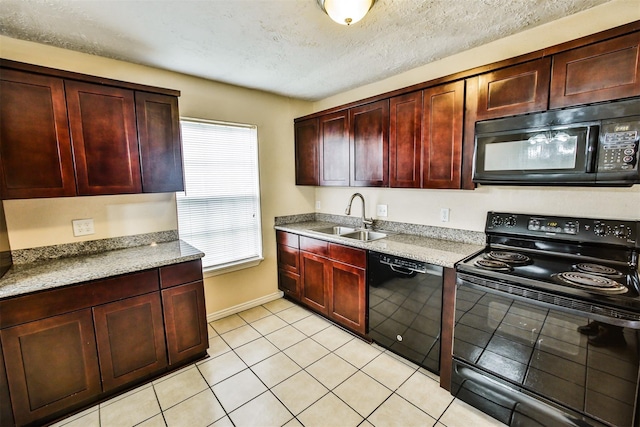 kitchen with light tile patterned floors, a sink, light stone countertops, reddish brown cabinets, and black appliances