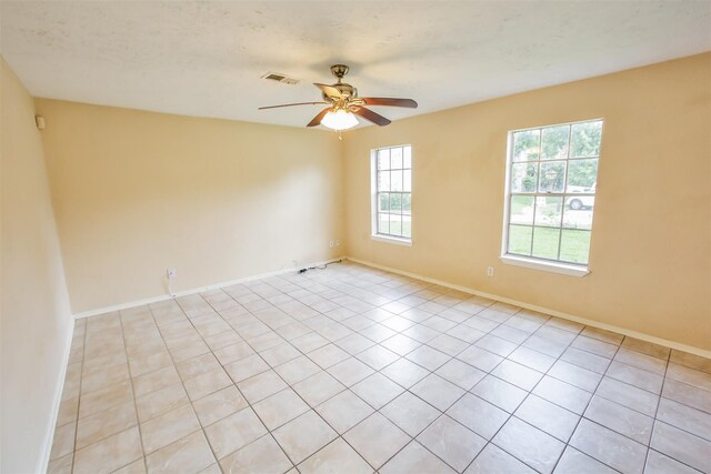 spare room with ceiling fan, visible vents, and baseboards