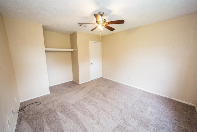 unfurnished bedroom featuring a textured ceiling, ceiling fan, carpet floors, visible vents, and a closet