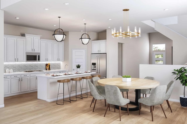 kitchen featuring pendant lighting, an island with sink, tasteful backsplash, white cabinetry, and stainless steel appliances