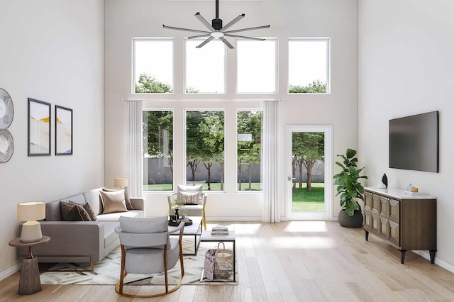 living room featuring ceiling fan, light hardwood / wood-style floors, and a high ceiling