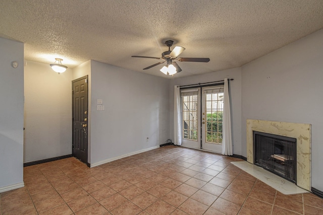 unfurnished living room with ceiling fan, french doors, a textured ceiling, a fireplace, and light tile patterned flooring