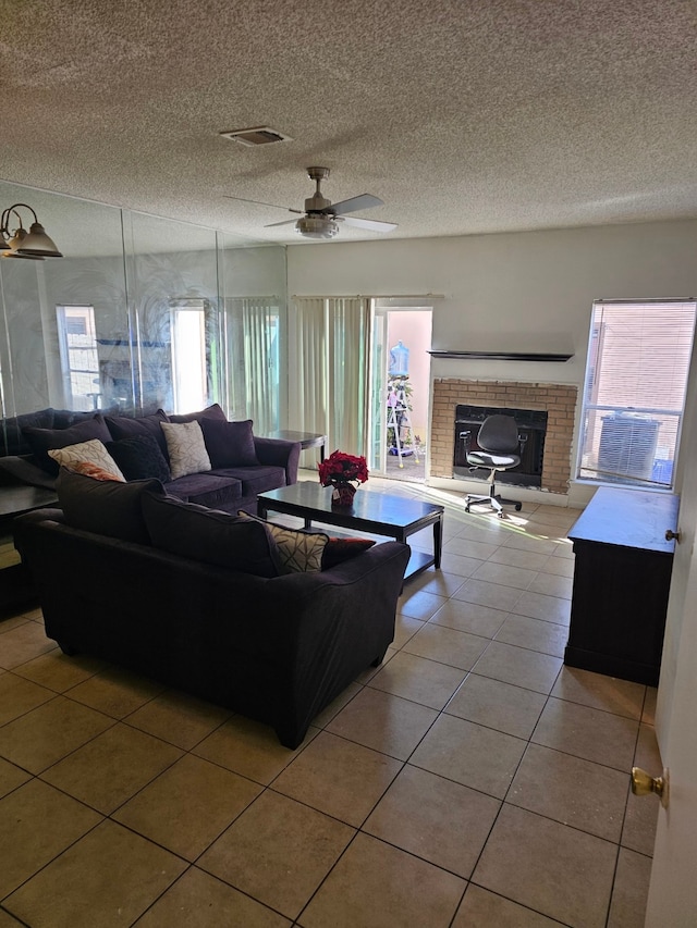 living room with a fireplace, light tile patterned floors, a textured ceiling, and ceiling fan