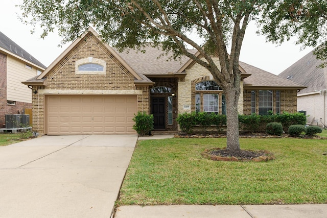 view of front of property featuring a front yard, a garage, and central AC unit