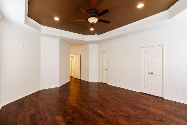 empty room featuring a raised ceiling, crown molding, dark hardwood / wood-style flooring, and ceiling fan