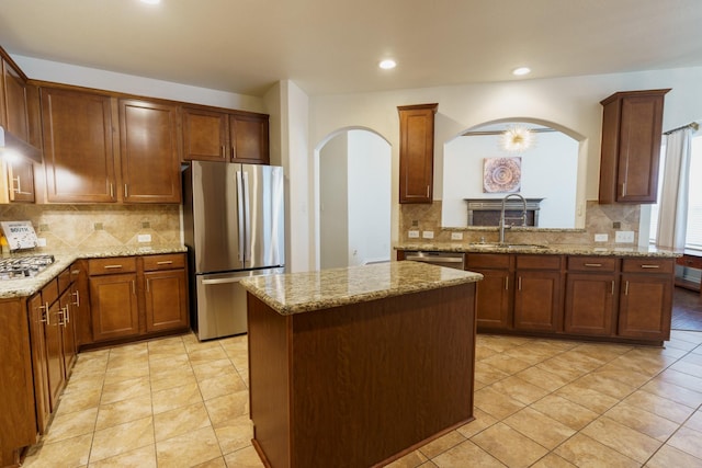 kitchen featuring kitchen peninsula, light stone counters, a kitchen island, and appliances with stainless steel finishes