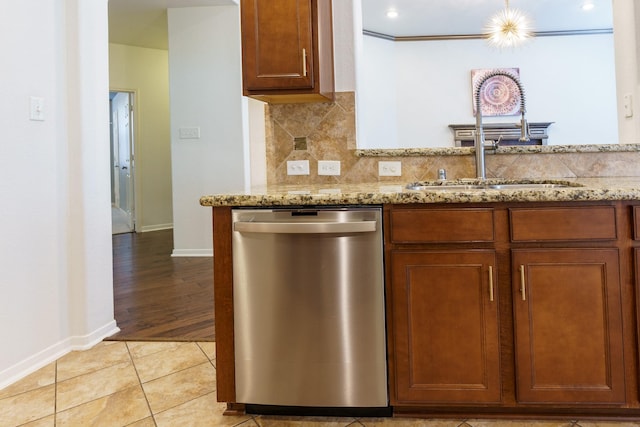 kitchen featuring light stone countertops, dishwasher, sink, backsplash, and light wood-type flooring