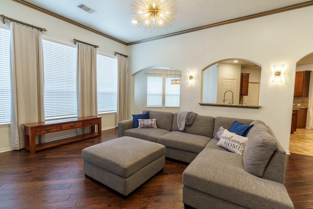 living room featuring a chandelier, dark hardwood / wood-style flooring, and crown molding