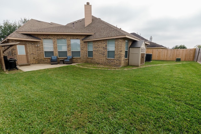 rear view of property with a lawn, a storage shed, and a patio