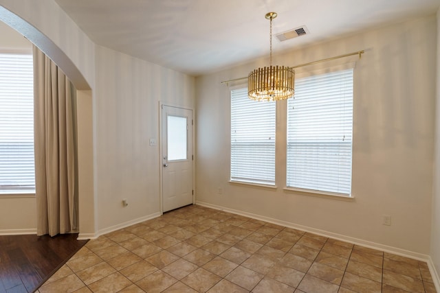 empty room featuring wood-type flooring and a chandelier