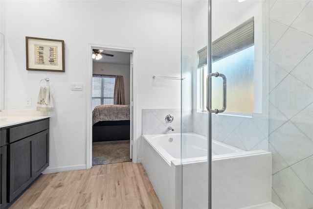 bathroom with ceiling fan, vanity, wood-type flooring, and plus walk in shower