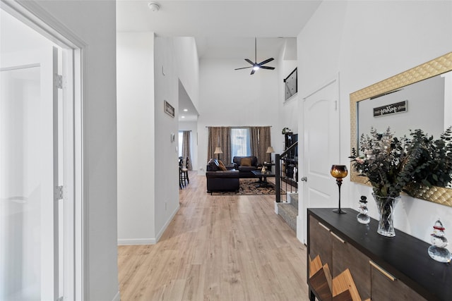 hall with a high ceiling and light hardwood / wood-style floors