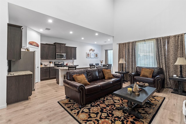 living room with light hardwood / wood-style floors and a high ceiling