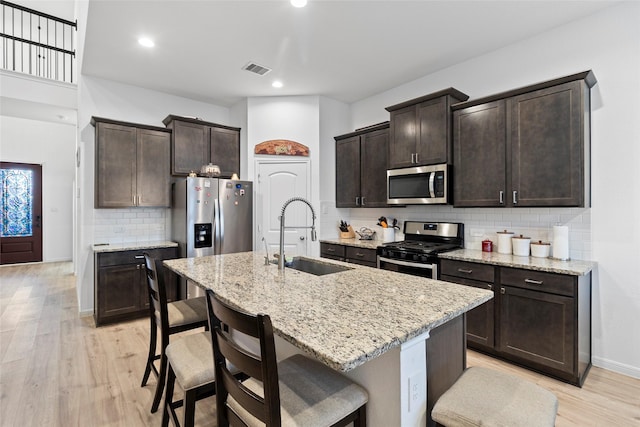 kitchen featuring sink, an island with sink, stainless steel appliances, and light hardwood / wood-style flooring