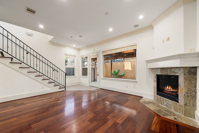 unfurnished living room featuring ornamental molding, a tiled fireplace, and hardwood / wood-style floors