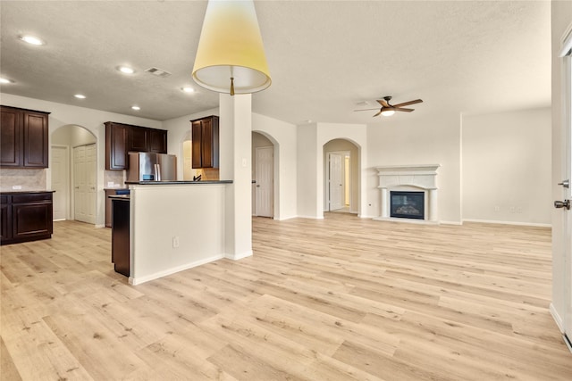 kitchen featuring dark brown cabinetry, ceiling fan, tasteful backsplash, light hardwood / wood-style flooring, and stainless steel fridge