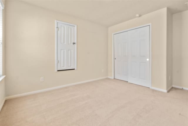 unfurnished bedroom featuring light carpet and a closet