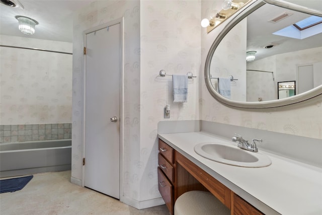 bathroom with a tub to relax in, vanity, and a skylight