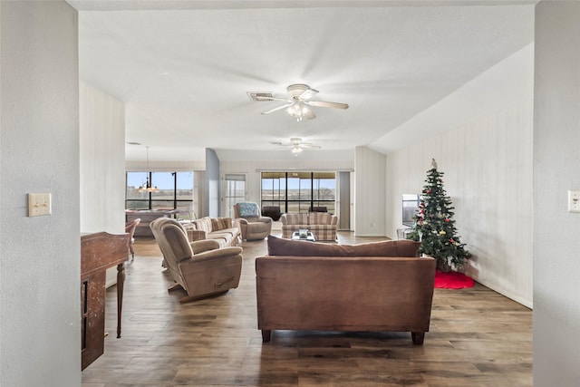 living room featuring ceiling fan with notable chandelier and dark hardwood / wood-style floors