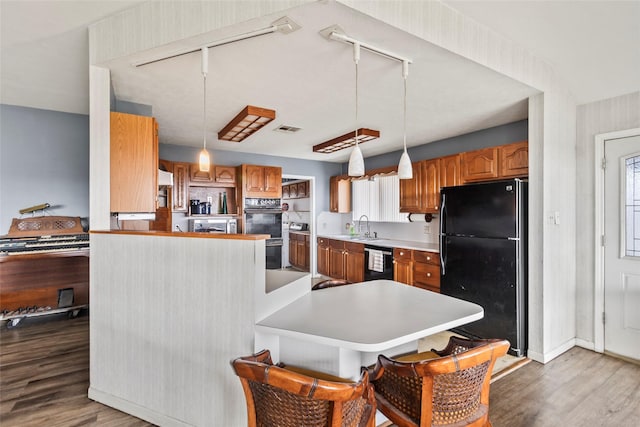 kitchen featuring sink, hanging light fixtures, black appliances, and light wood-type flooring