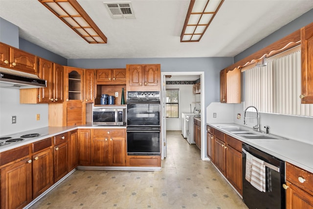 kitchen with washing machine and clothes dryer, sink, and black appliances