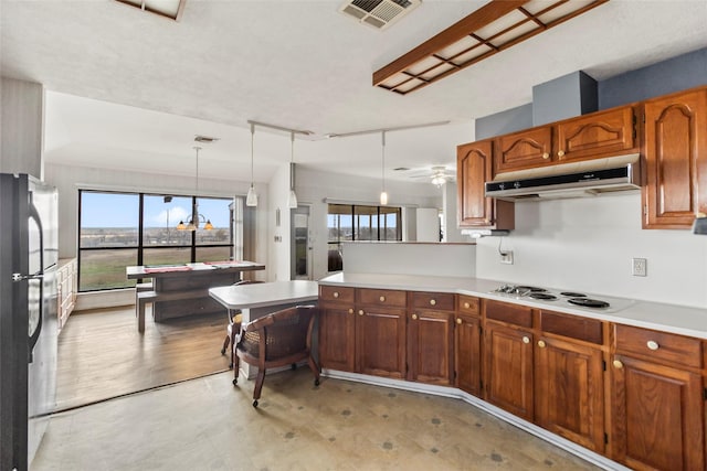 kitchen featuring ceiling fan, white stovetop, kitchen peninsula, refrigerator, and decorative light fixtures