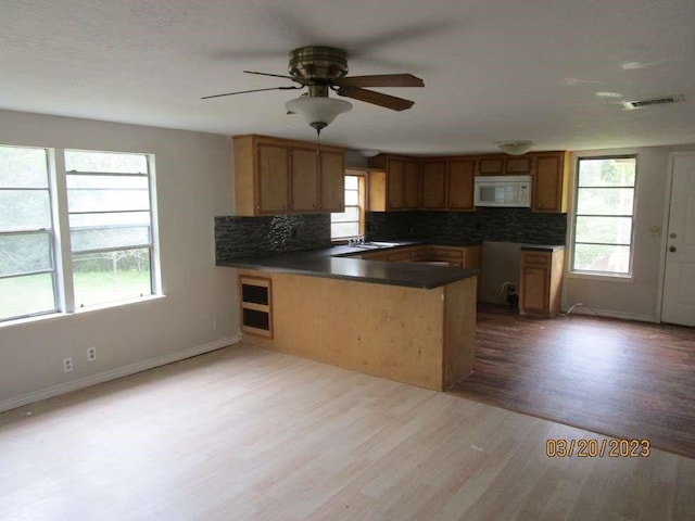 kitchen with sink, decorative backsplash, ceiling fan, light wood-type flooring, and kitchen peninsula