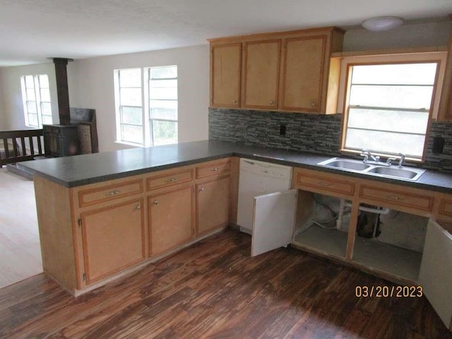 kitchen featuring a wood stove, sink, dark wood-type flooring, kitchen peninsula, and decorative backsplash