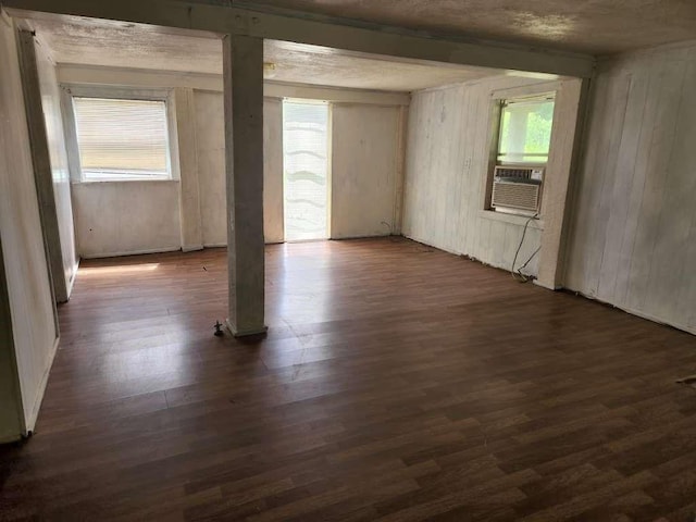 empty room with wooden walls, dark hardwood / wood-style floors, cooling unit, and a wealth of natural light