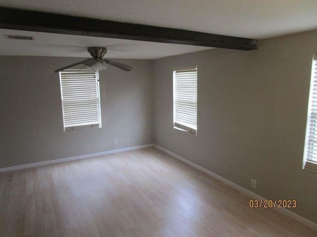 empty room featuring beam ceiling and light hardwood / wood-style floors