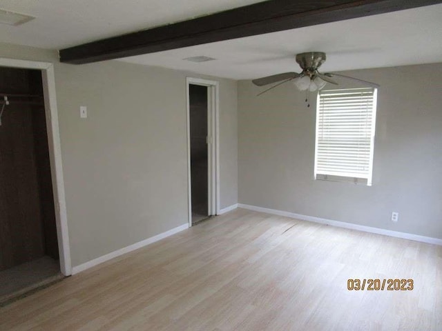 unfurnished bedroom with beam ceiling, a closet, light hardwood / wood-style flooring, and ceiling fan