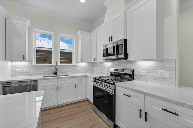 kitchen with white cabinets, decorative backsplash, sink, and stainless steel appliances