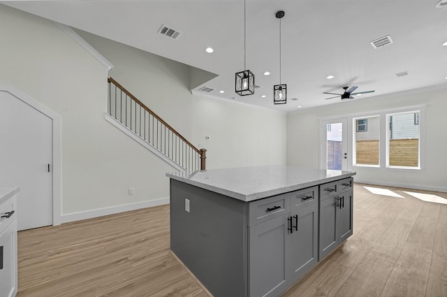 kitchen featuring ceiling fan, decorative light fixtures, gray cabinets, light hardwood / wood-style floors, and a kitchen island