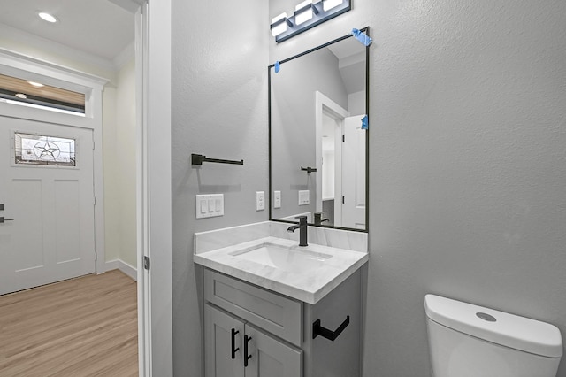 bathroom with hardwood / wood-style floors, vanity, and toilet