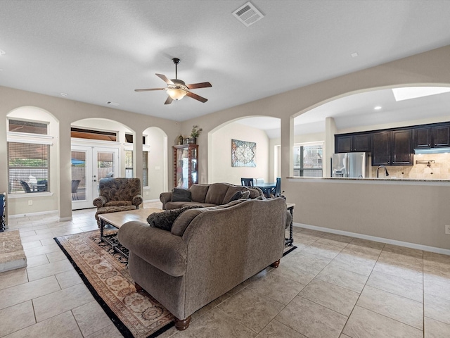 tiled living room with ceiling fan and french doors