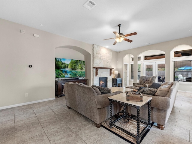 living room featuring a fireplace, ceiling fan, and french doors