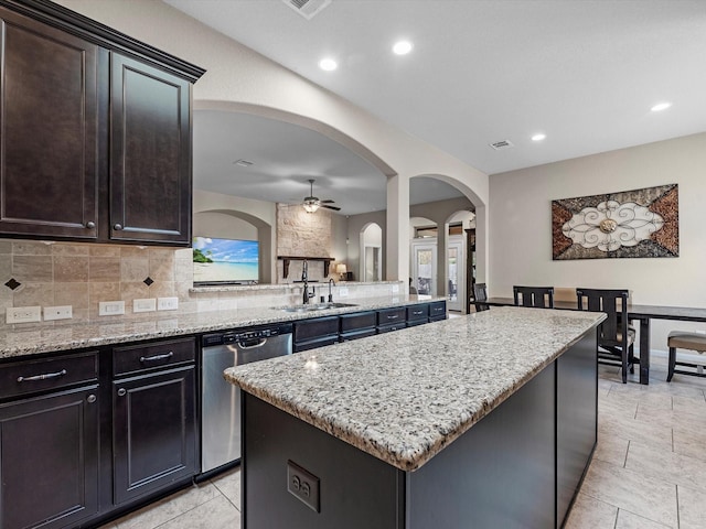 kitchen with sink, a center island, light stone counters, and stainless steel dishwasher