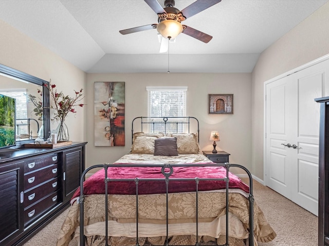 carpeted bedroom featuring a textured ceiling, a closet, vaulted ceiling, and ceiling fan