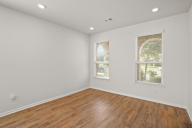 spare room with a healthy amount of sunlight, a textured ceiling, and wood-type flooring