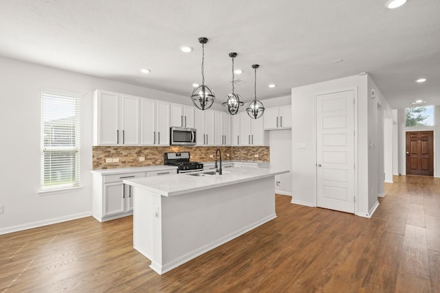 kitchen featuring white cabinets, stainless steel appliances, hardwood / wood-style flooring, and an island with sink