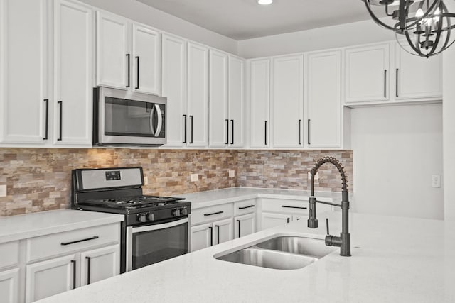 kitchen with backsplash, stainless steel appliances, white cabinetry, and sink