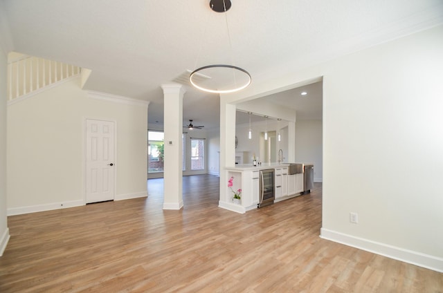 interior space with light hardwood / wood-style flooring, beverage cooler, ornamental molding, and ceiling fan