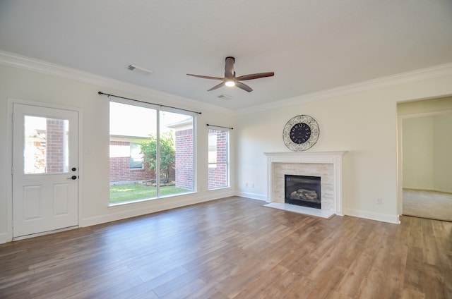 unfurnished living room featuring hardwood / wood-style floors, ceiling fan, crown molding, and a tiled fireplace