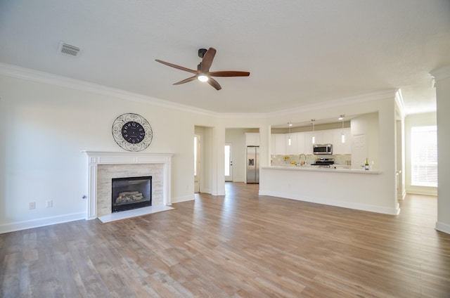 unfurnished living room with light hardwood / wood-style flooring, ceiling fan, ornamental molding, and sink