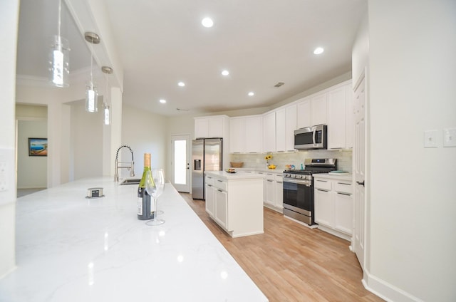 kitchen featuring decorative light fixtures, light wood-type flooring, white cabinetry, and stainless steel appliances